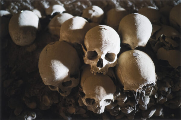 Cluster of skulls with coins on top of their crowns at the Cimitero delle Fontanelle ossuary in Napoli Italy.