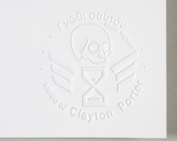 Embossed stamp on rag paper with the image of a human skull above a hourglass with wings with the Greek text know thyself above and studio of Clayton Porter below.